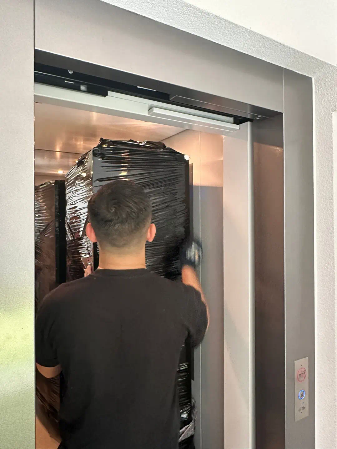 Diversa Group Mitarbeiter platziert ein Möbelstück sicher im Aufzug während des Auslandsumzugs
